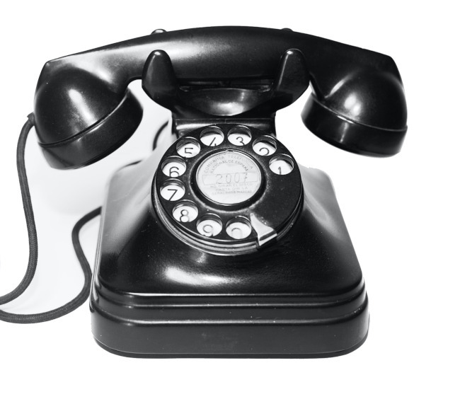crni starinski telefon sa brojčanikom na beloj pozadini
