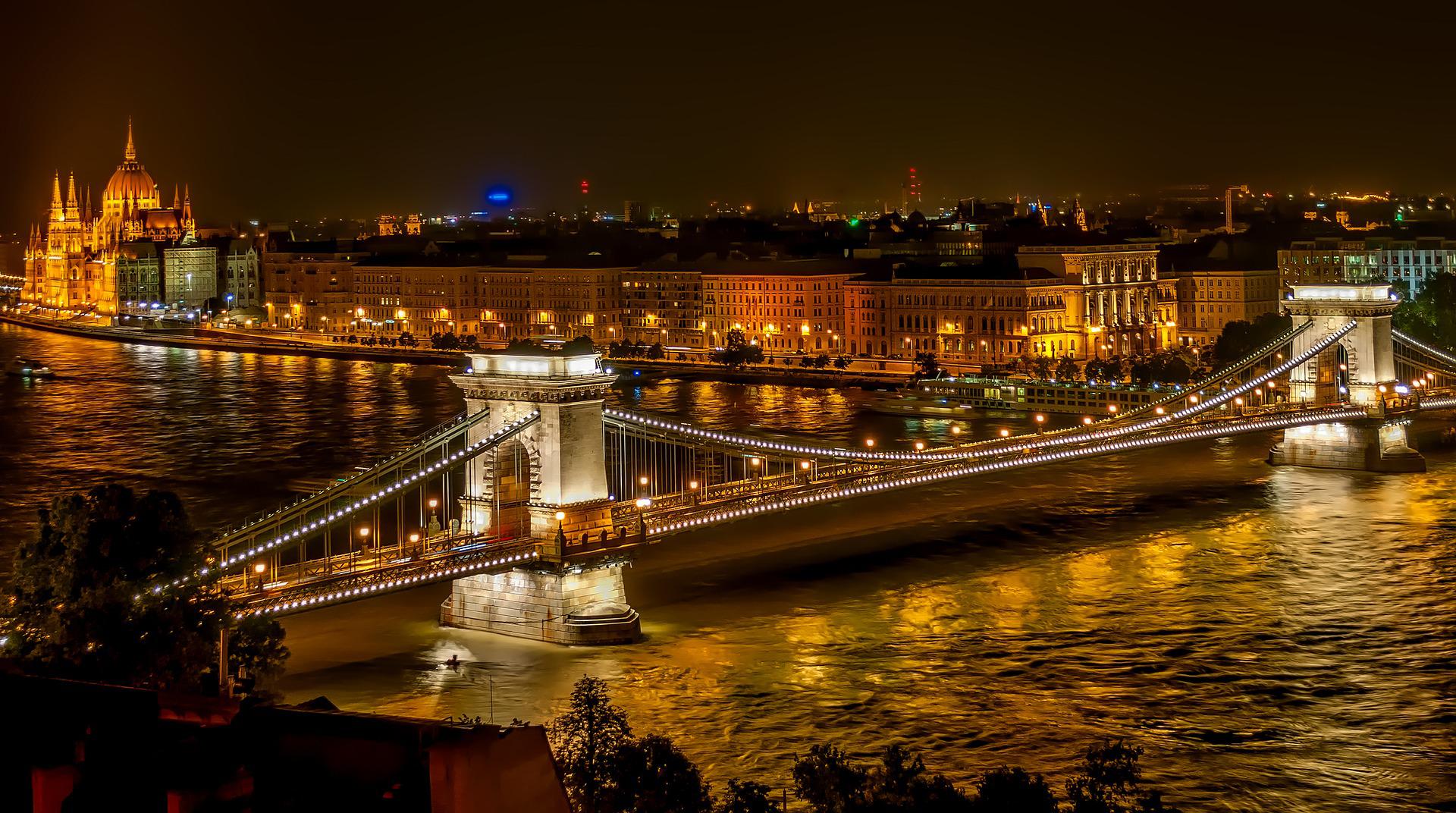 Lančani most u Budimpešti preko Dunava noću sa zgradom parlamenta u pozadini